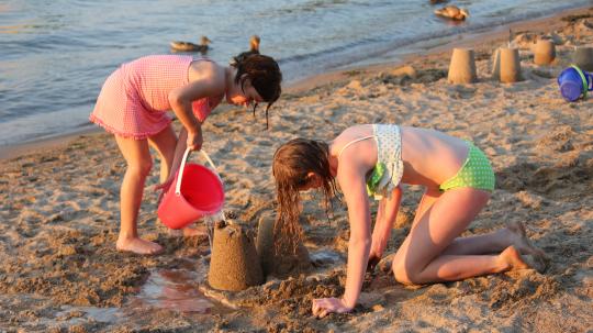 Girls build a sandcastle at the water's edge