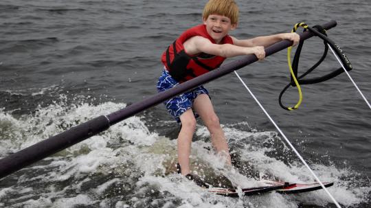Young boy smiling as he learns how to water ski