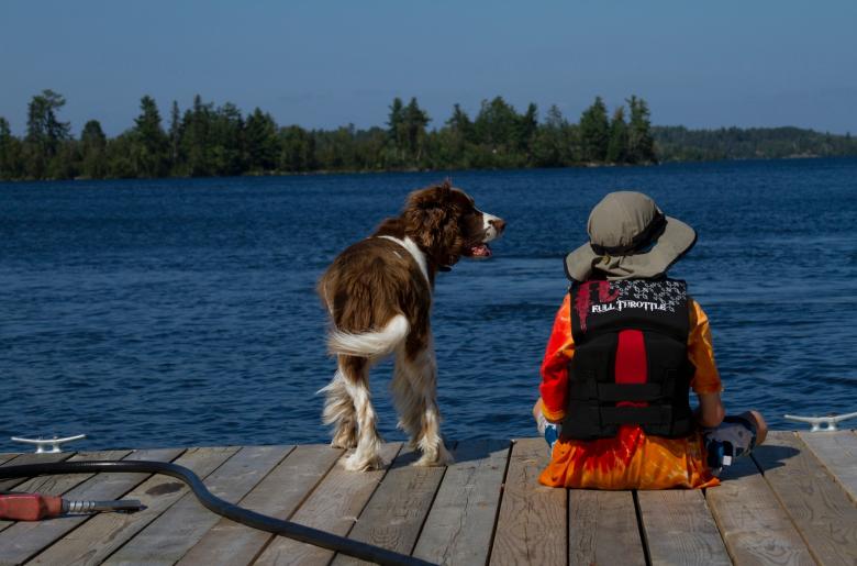 Boy and dog sitting on the dock