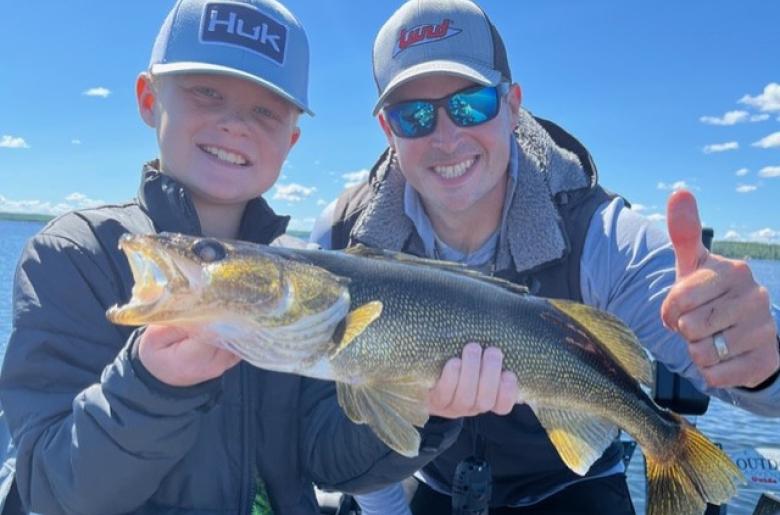 Guide Jason Freed and a child smiling with a keeper walleye