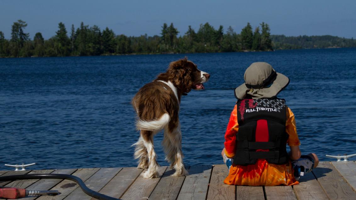 Boy and dog sitting on the dock