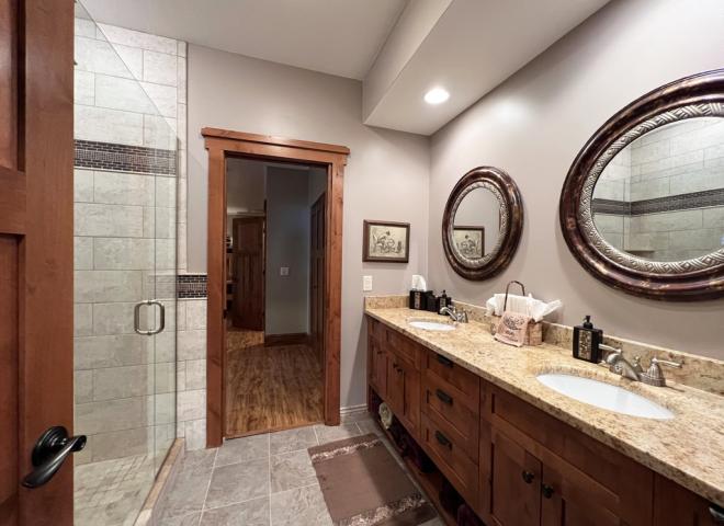 Downstairs bathroom with double sink, shower, and granite.