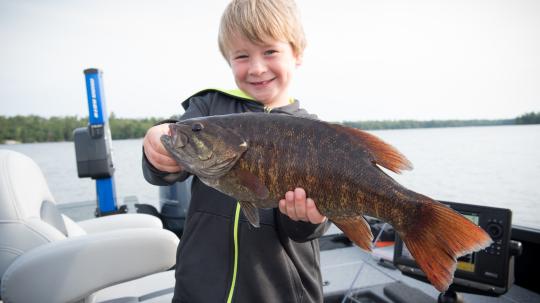Young boy proudly holding a bass