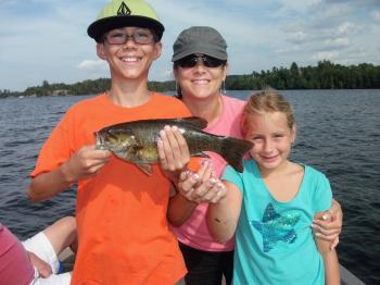 A family smiles with a bass on Lake Vermilion