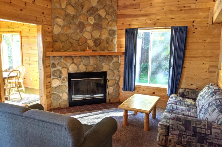 Living room with couch, loveseat, and wood burning fireplace.
