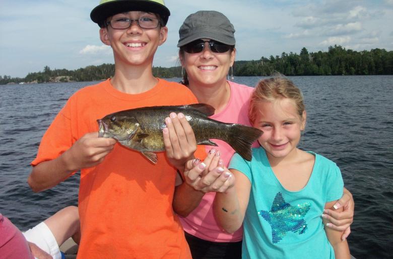 A family smiles with a bass on Lake Vermilion