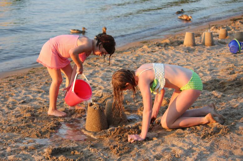 Girls build a sandcastle at the water's edge