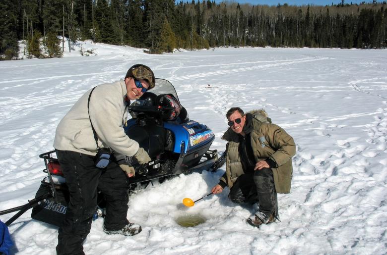 Men ice fishing with a snowmobile
