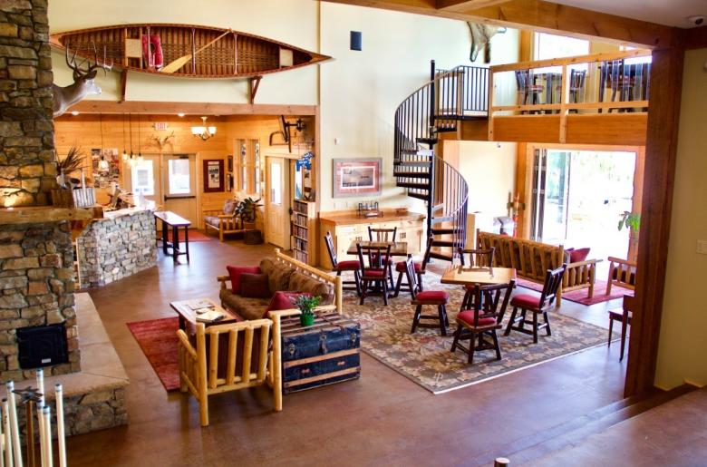 Main lodge with stone fireplace, plenty of seating, and loft view of the lake.