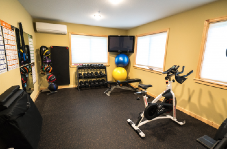 Fitness room with TV, workout mats, and a variety of equipment.