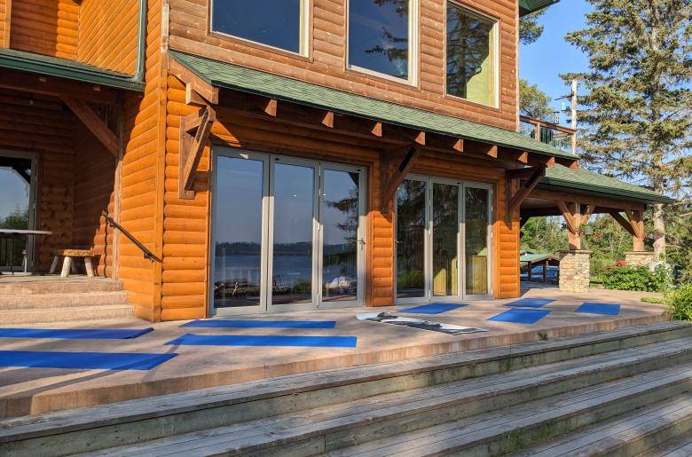 Front of the lodge with yoga mats set up facing the lake.
