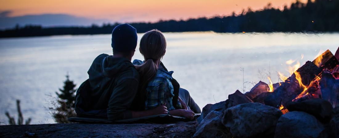 Couple sitting by the fire on Lake Vermilion at sunset.